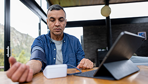 home blood pressure monitor man sitting at table