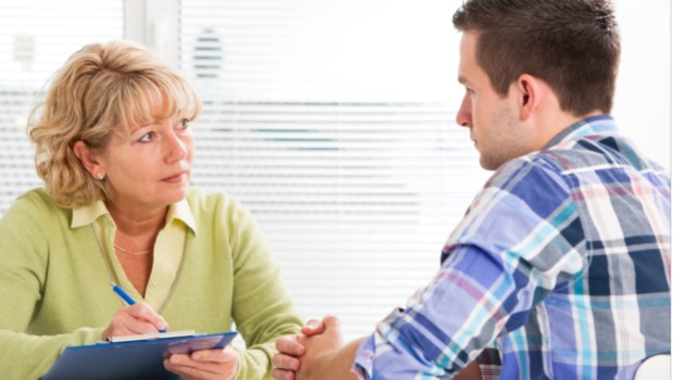 Woman clinician sitting across from male patient.