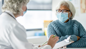 Female doctor and senior female patient sitting around desk